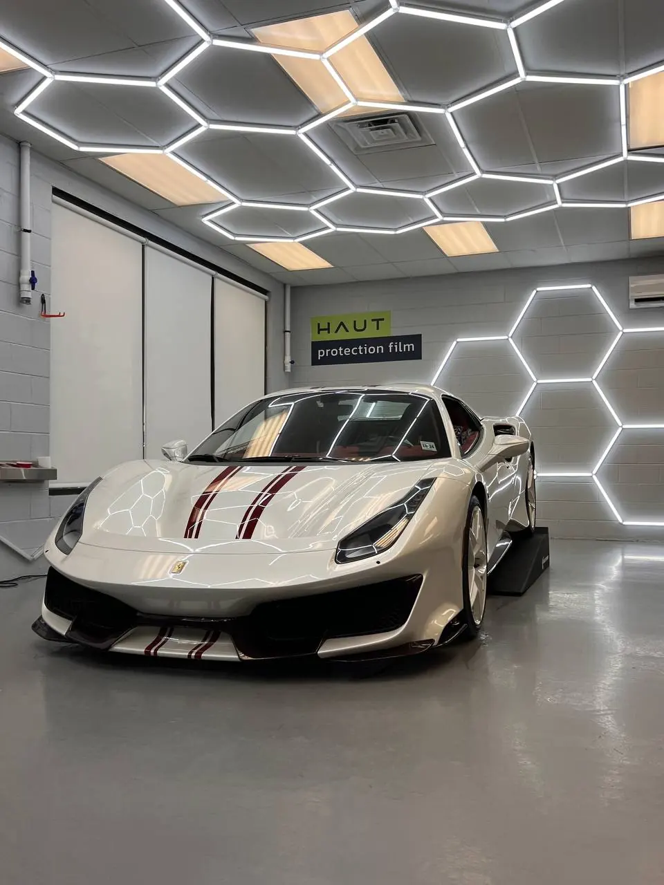 White Ferrari 488 Pista under the hex lighting of the install bay