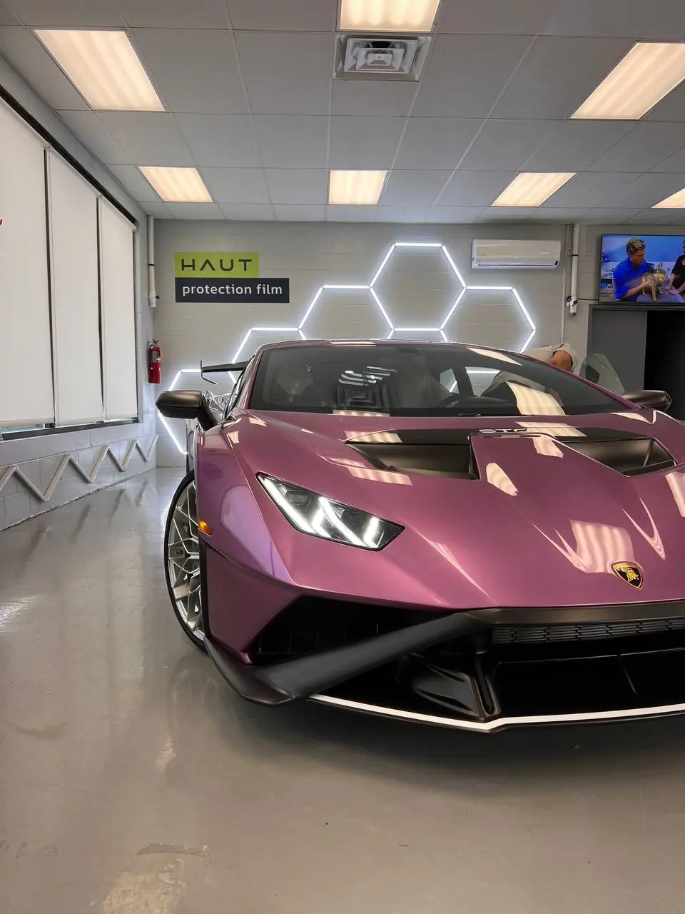 Purple Lamborghini Huracán STO under the hex lighting of the install bay
