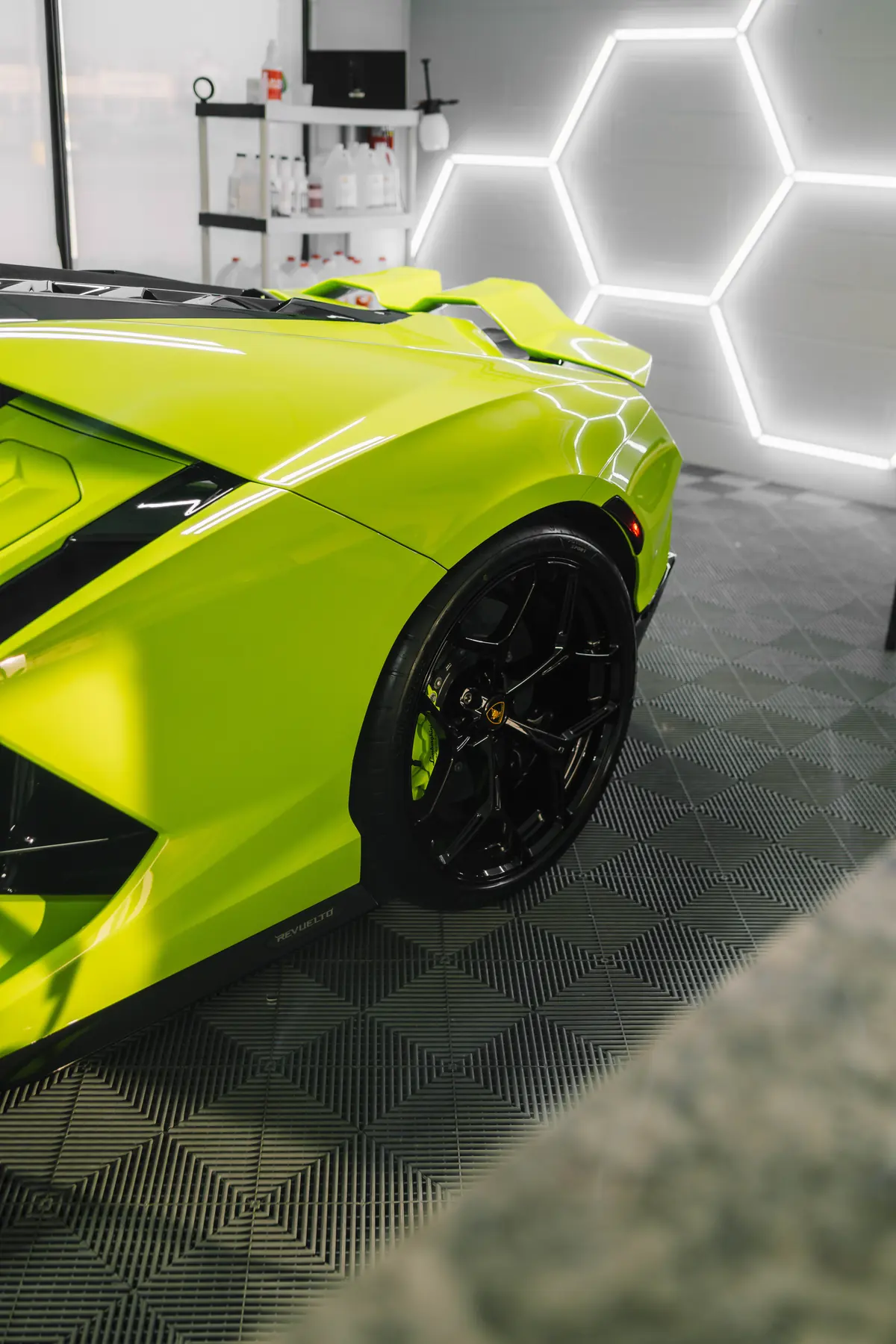 Rear quarter of a lime Lamborghini Revuelto in the install bay