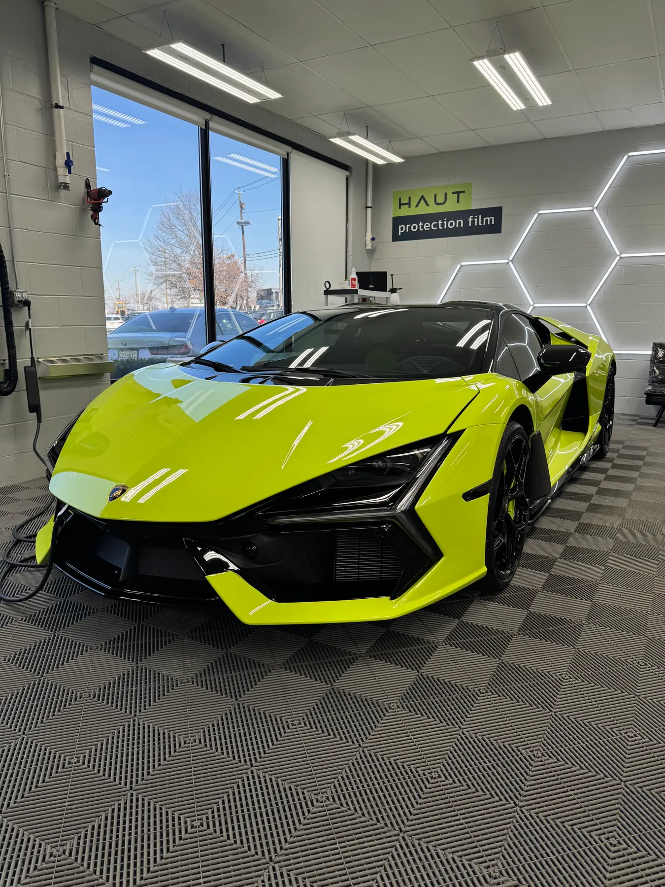 Lime Lamborghini Revuelto under the hex lighting of the install bay