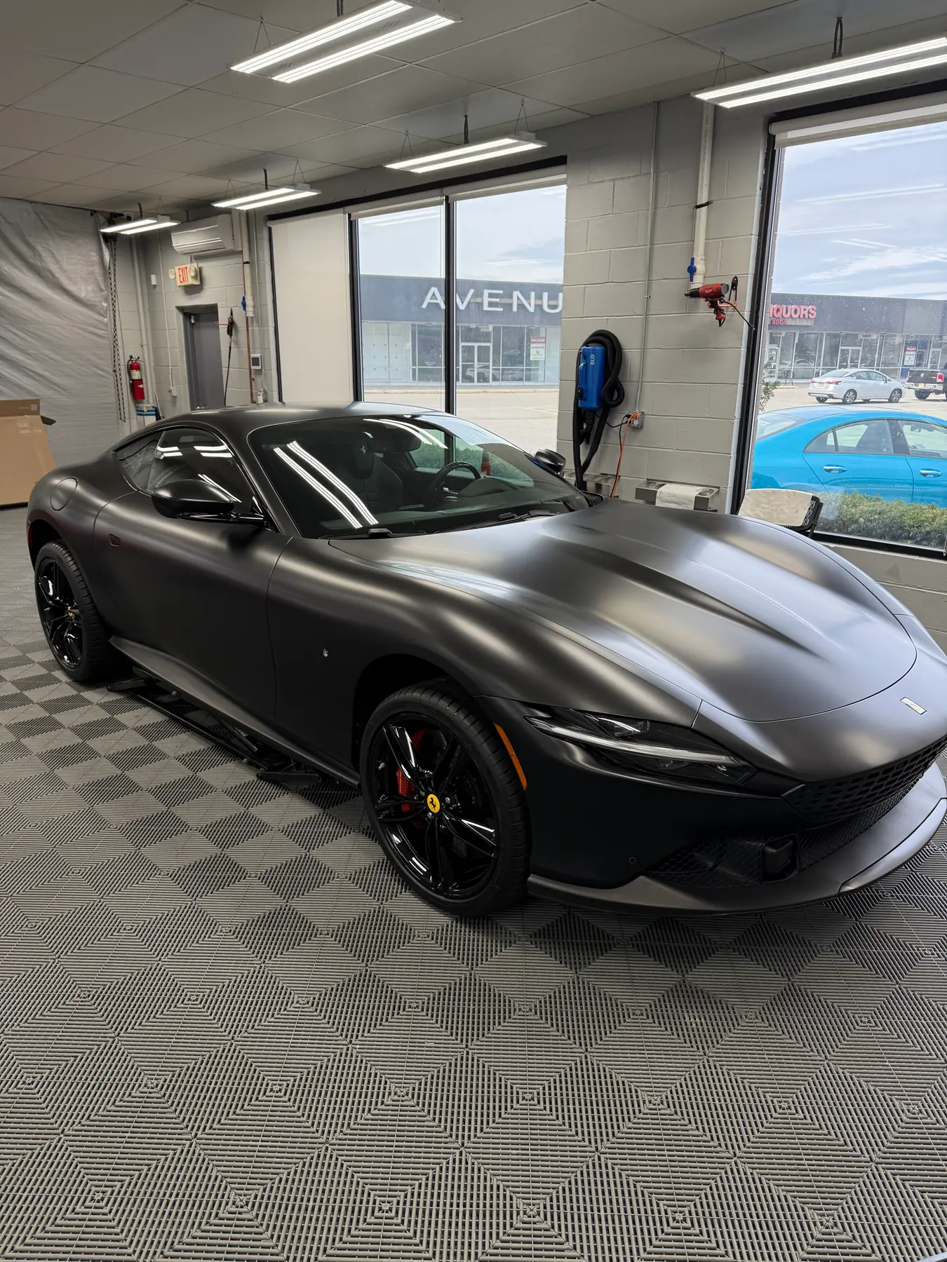 Matte black Ferrari Roma under the bay lighting