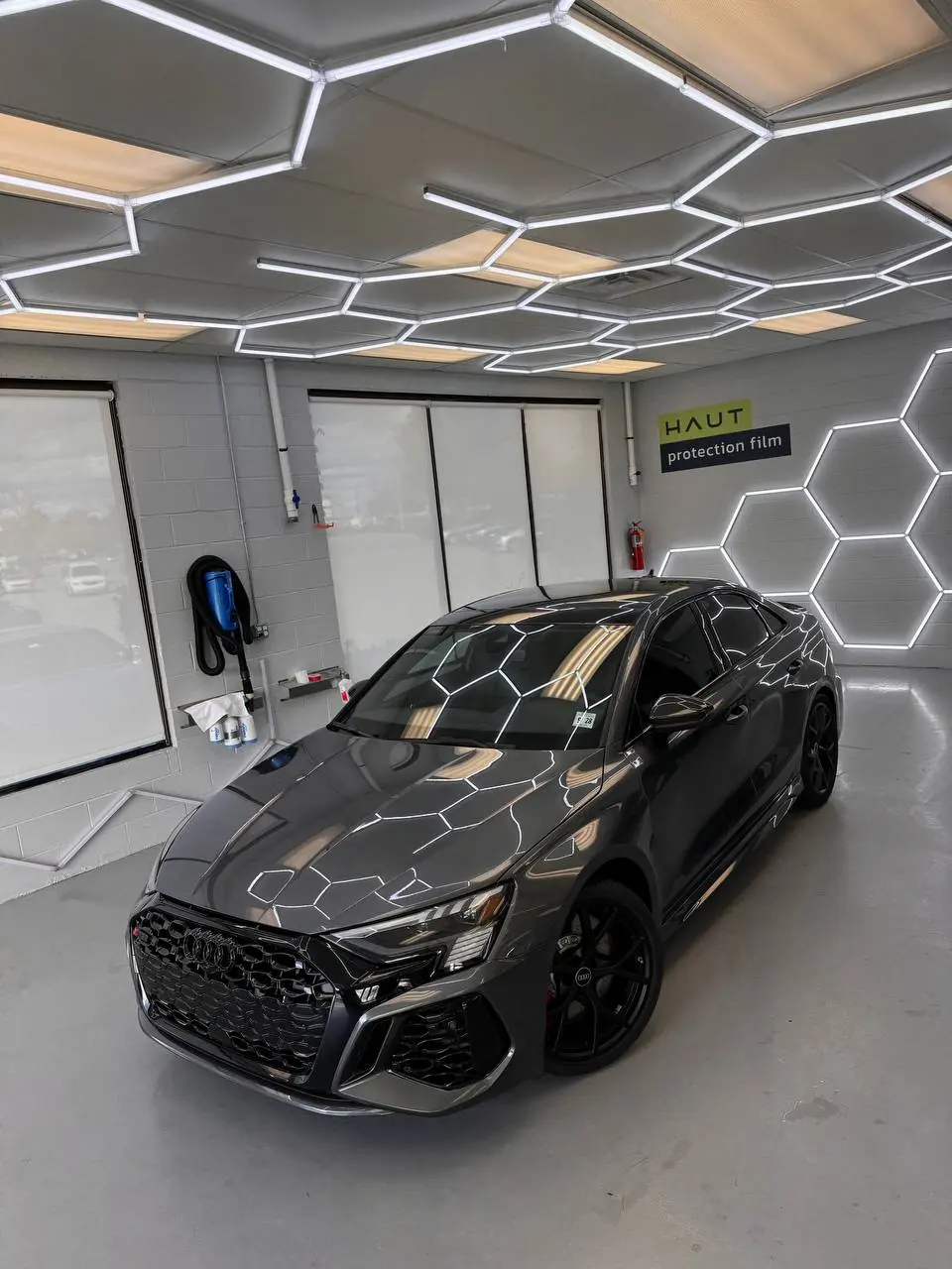 Black Audi RS 3 under the hex lighting of the install bay