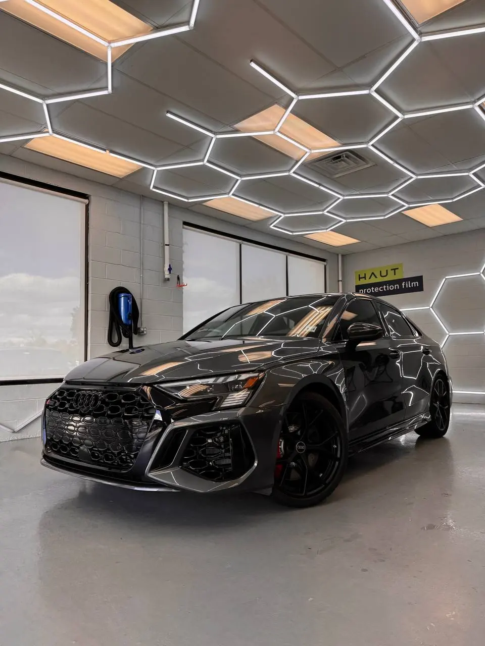 Rear three-quarter of a black Audi RS 3 in the install bay