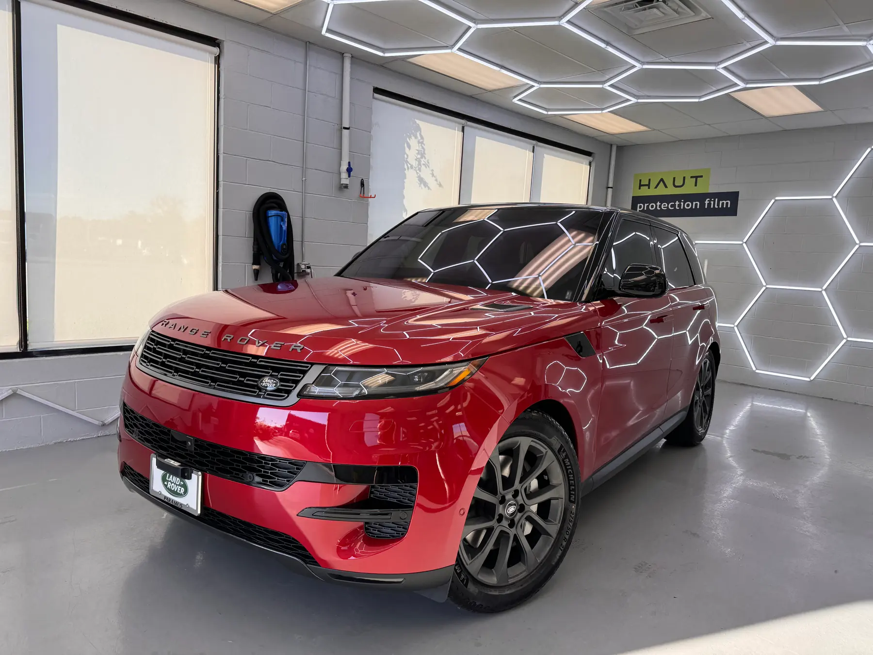 Film being fitted to the front end of a red Range Rover Sport