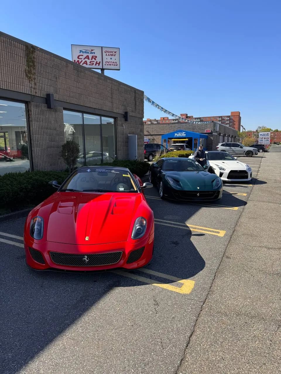 Row of sports cars waiting outside the shop, red Ferrari in front