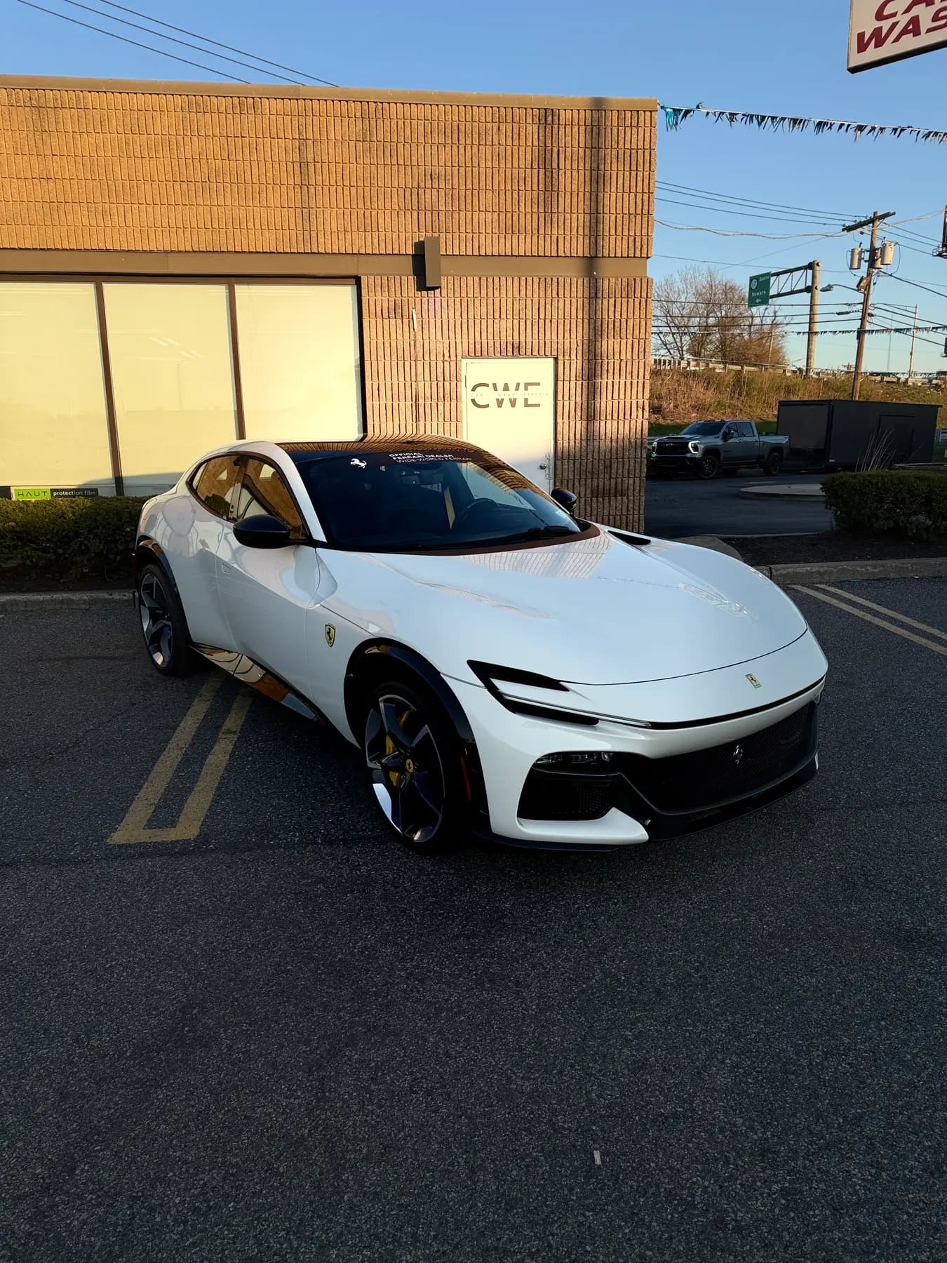 Rear three-quarter of a white Ferrari Purosangue outside the shop